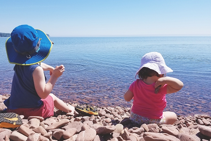 Two little girls playing on the rocks on a beach in Maine