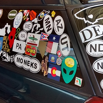 Closeup of numerous state travel decals adorning the Subaru Outback windows. 