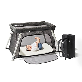 A female infant laying in the travel crib, with the side unzipped demonstrating easy ways for a child  and parent to use it with it’s travel backpack next to it