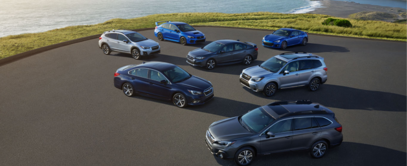 Subaru models in a parking lot, including the WRX, Legacy, Outback, Forester and BRZ