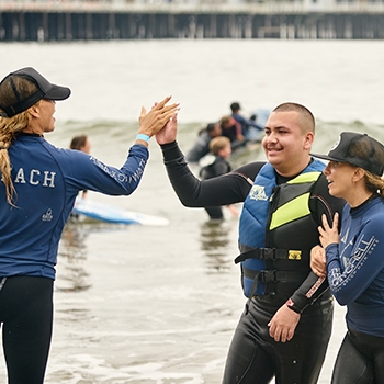 Surf instructor high-fives a student