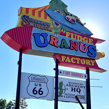 Shot of Uranus Fudge Factory's multicolored neon sign, which includes an image of the highway sign for Route 66