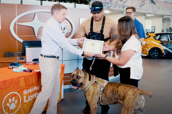 Subaru of Las Vegas employees spent about 100 hours training therapy dogs. One employee with his therapy dog is being awarded a certificate in the retailer's showroom.