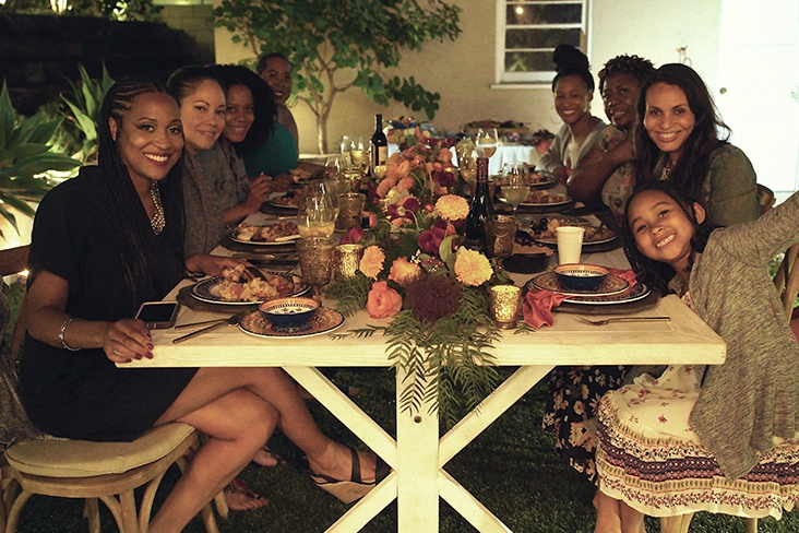 Grant and her smiling guests seated at the dinner table