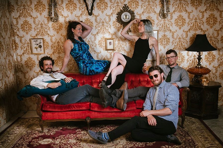 Pixie and the Partygrass Boys band members posing in a living room setting. 