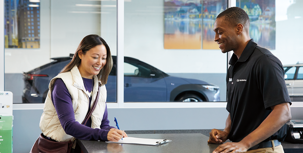 A customer and a finance and insurance representative at a Subaru retailer discussing finance options on a Subaru Solterra