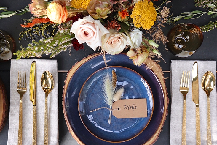 A festive fall place setting, featuring floral arrangements, dinnerware and place cards.