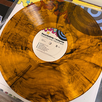A shot of the record for the Fountains of Wayne album Traffic and Weather. It is orange-colored vinyl with black streaks.