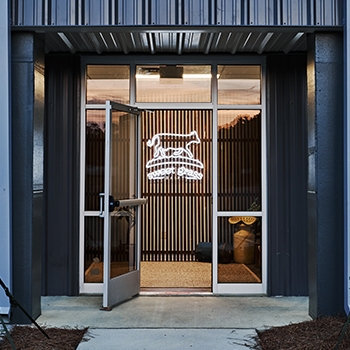 Sweetgrass production facility with a neon light illuminated in the shape of a cow.