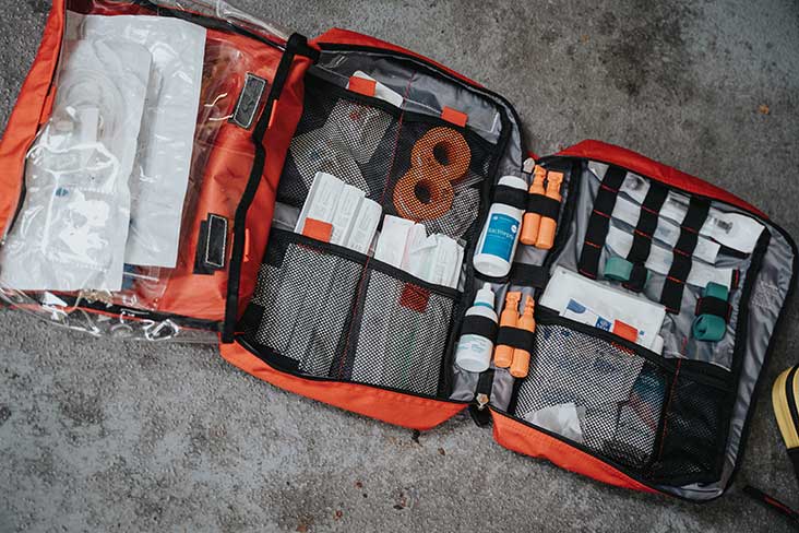 A large red medical kit is open on the ground revealing medical supplies inside.