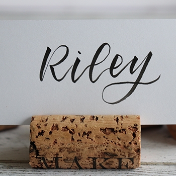 Riley written stylishly on a white card inserted in a wine cork place card holder.