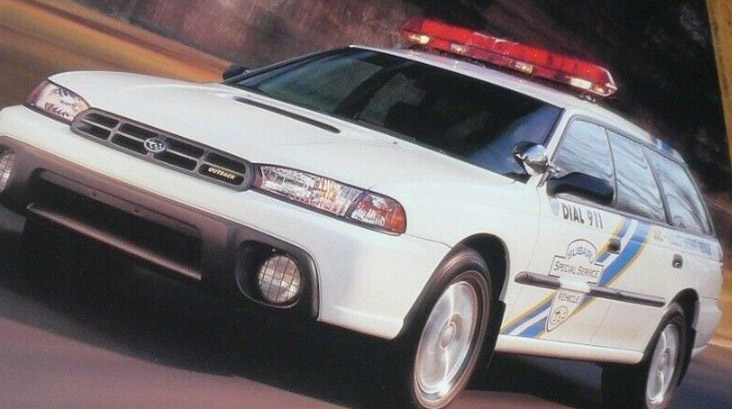 The Subaru Outback SSV, or Special Service Vehicle. It is white with red lights on the roof, and DIAL 911 is written in black lettering on driver's door along with the badge Subaru Special Service Vehicle.