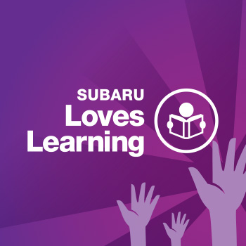 Subaru Loves Learning logo in white lettering on a purple background. To the right of the words “Subaru Loves Learning” is an illustration of a person reading a book, which is enclosed in a circle. Below it, hands are shown reaching up toward the circle. 