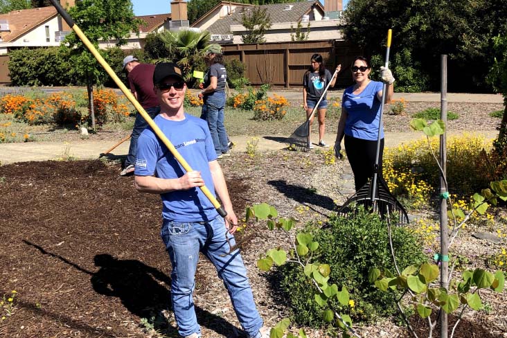 Volunteers pose with gardening tools at a community garden in Modesto, California.