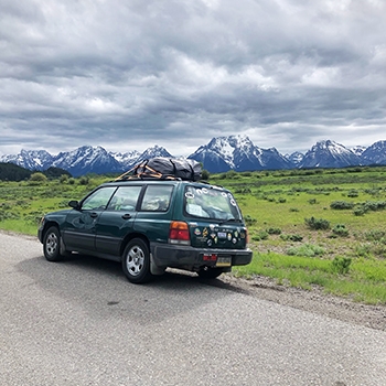 The Forester parked along the side of the road with mountains in the background