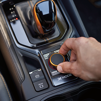 Close-up of a hand turning the knob of the Enhanced Dual-Function X-MODE feature of the Subaru Forester Wilderness.