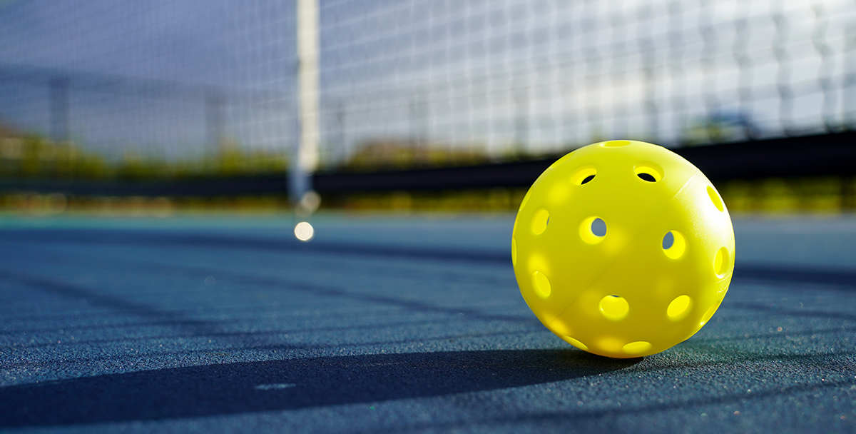 A bright-colored pickleball on a court