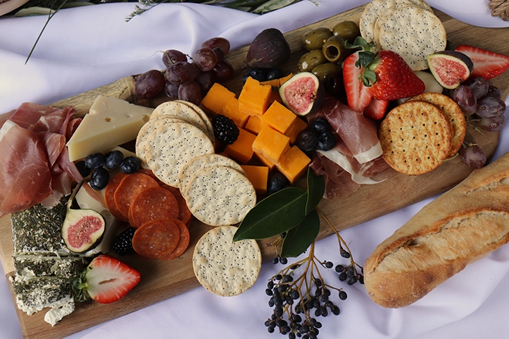 A large charcuterie board featuring a variety of fruits, cheese and crackers.