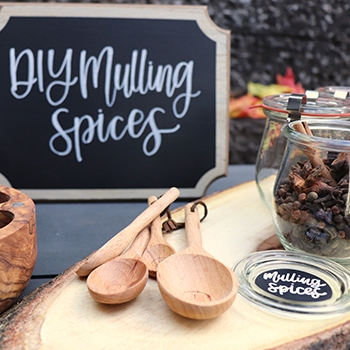 DIY mulled spices station with wooden spoons and jars of ingredients.