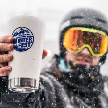 Snowboarder holding a Subaru Winterfest cup