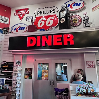 Interior view of the Fanning 66 Outpost, which has a variety of automobile-related signs over a doorway with double doors that says Diner