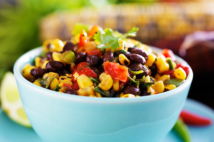 A full bowl of charred corn salsa salad with bright colors among the ingredients.
