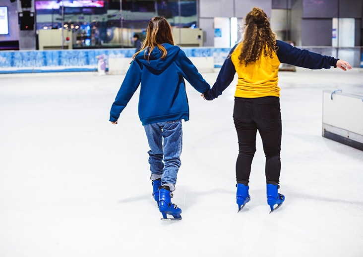 Two girls ice skating indoors