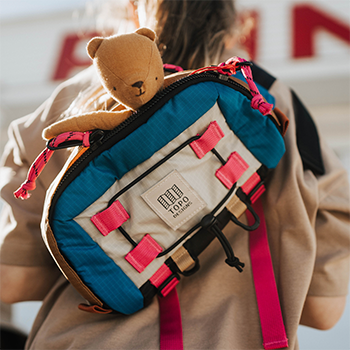 Close-up of a colorful backpack with a teddy bear sticking halfway outside of it