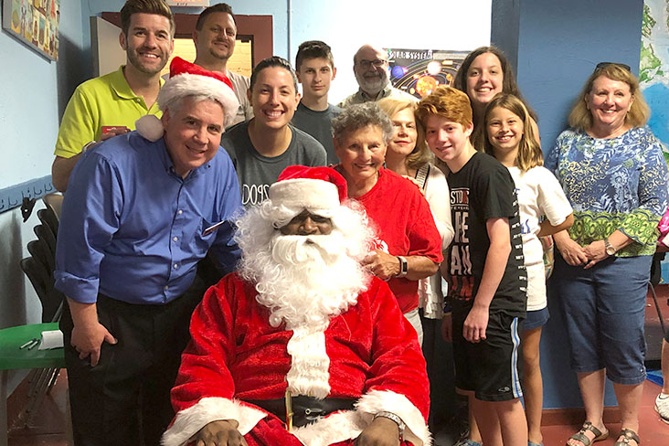 Rita Swiener poses with Santa and several people.