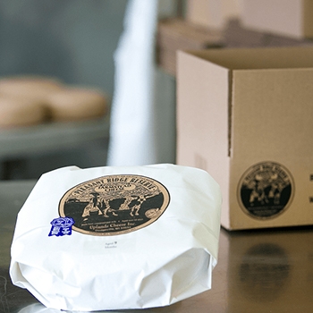 Pleasant Ridge Reserve cheese on display in white paper packaging.