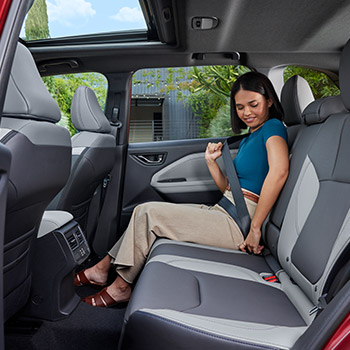 The interior rear seatback of the 2025 Subaru Forester with a female model seated next to a window.