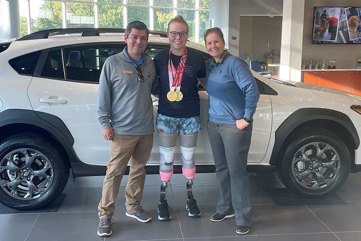 Morgan Stickney at the Subaru retailer with her Subaru Crosstrek Sport. She is standing between two Subaru staff.