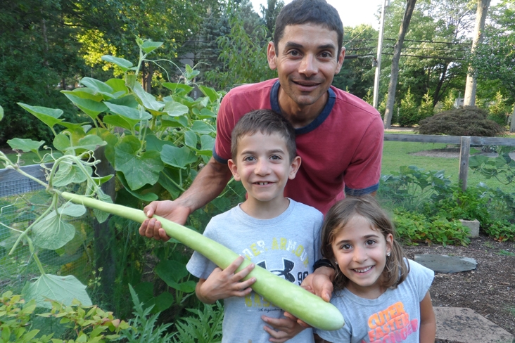 kids and dad holding a large cucuzza squash