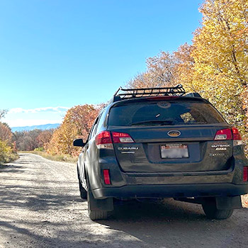 A shot of Caleb Calder's Subaru Outback, Perry, from behind on a gravel road in a rural setting.