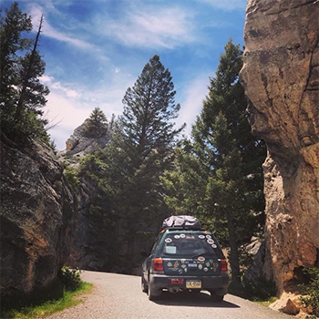 The Forester packed with gear driving through a wooded canyon