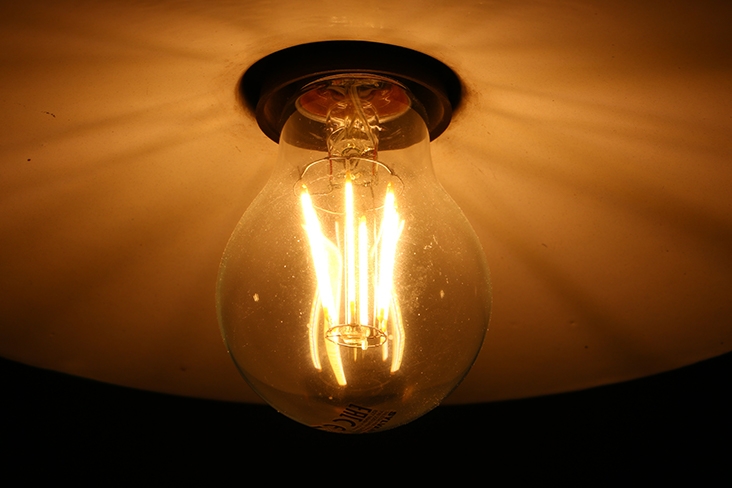A warm lightbulb on a ceiling in a dark room.