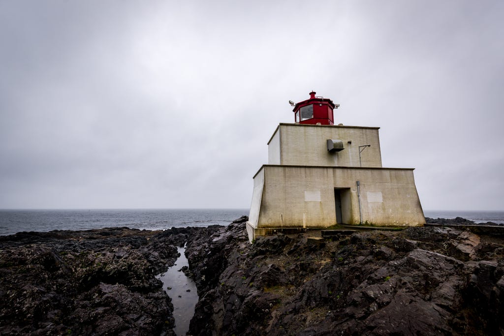 A lighthouse on a rocky coast, with an overcast sky A lighthouse on a rocky coast, with an overcast sky