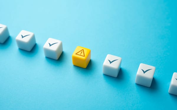 A row of white cubes on a blue background. The cubes contain checkmarks, with a yellow cube in the middle containing an alert symbol. A row of white cubes on a blue background. The cubes contain checkmarks, with a yellow cube in the middle containing an alert symbol.