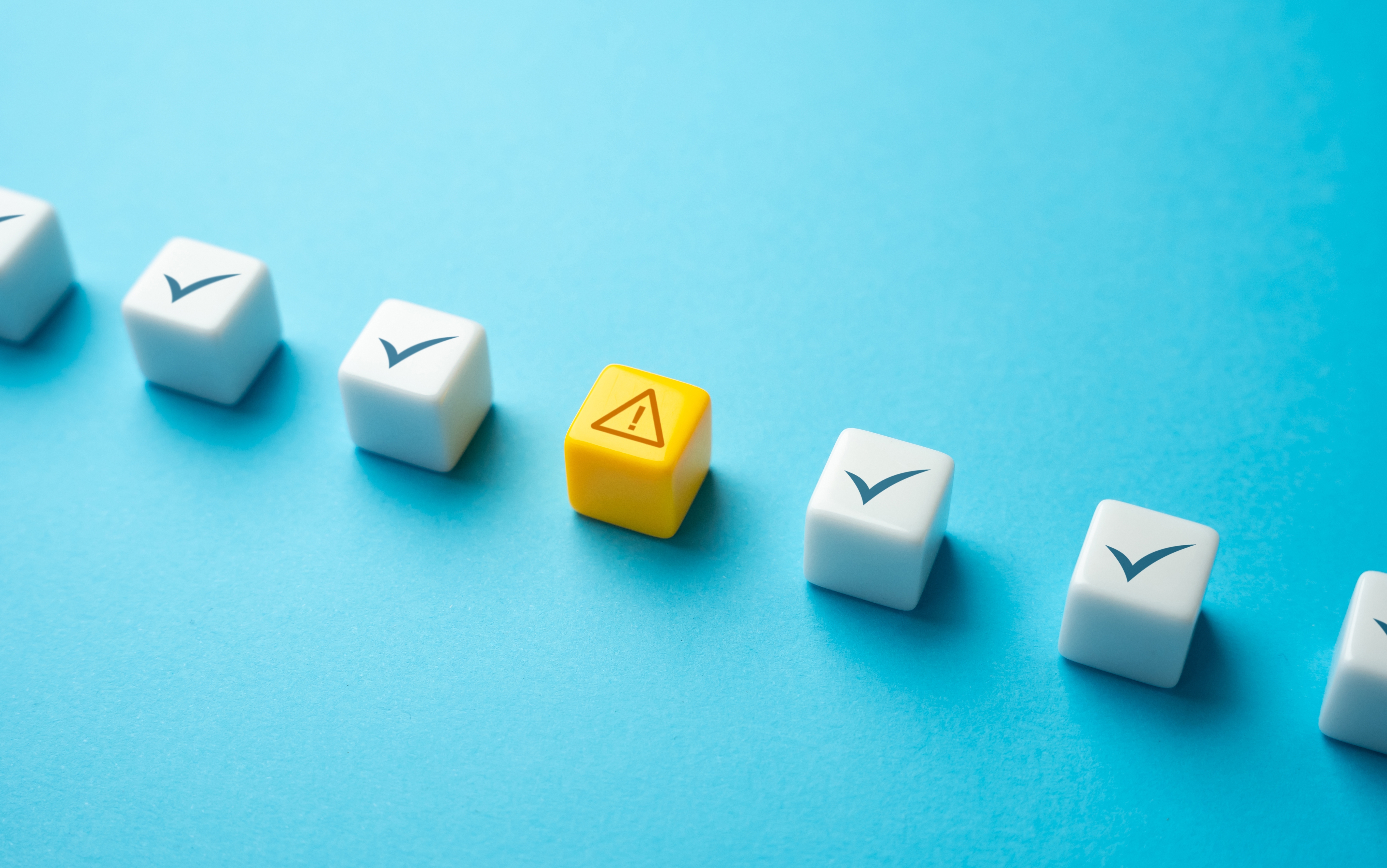 A row of white cubes on a blue background. The cubes contain checkmarks, with a yellow cube in the middle containing an alert symbol.