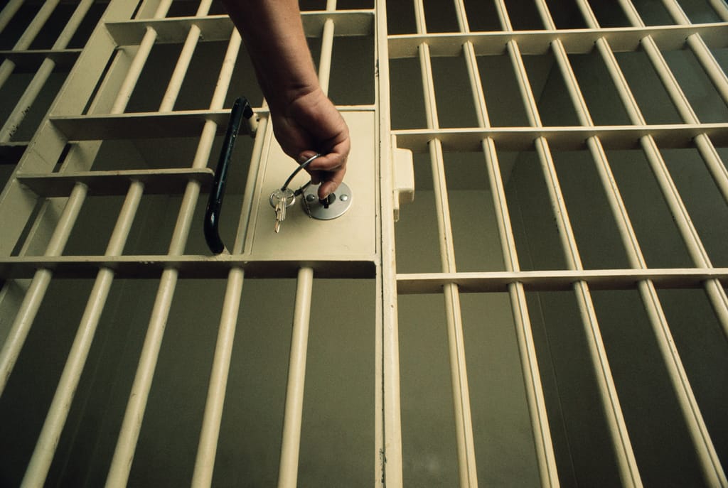 A photograph of a hand reaching out to lock a prison cell with a bunch of keys A photograph of a hand reaching out to lock a prison cell with a bunch of keys