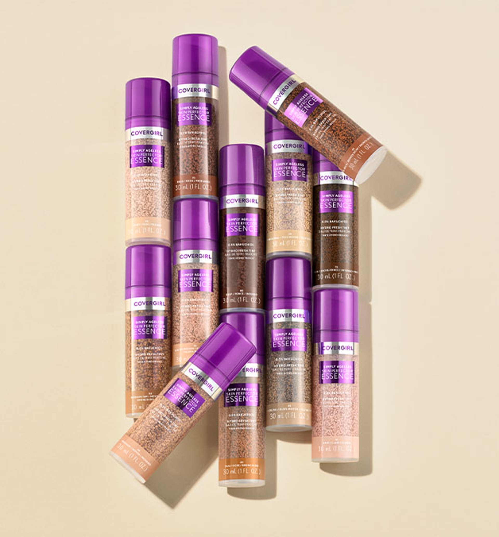 Eleven Covergirl foundation bottles with purple caps arranged neatly on a beige background.