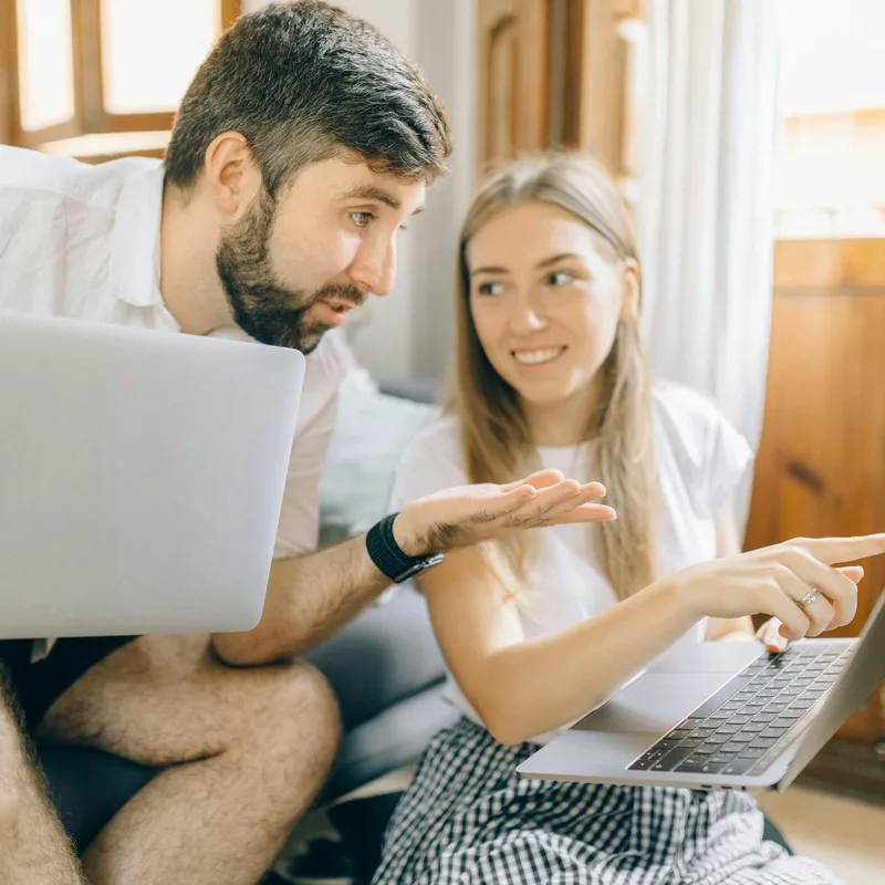 Hombre y mujer sentados frente a una laptop cada uno para estudiar el nivel básico de inglés.