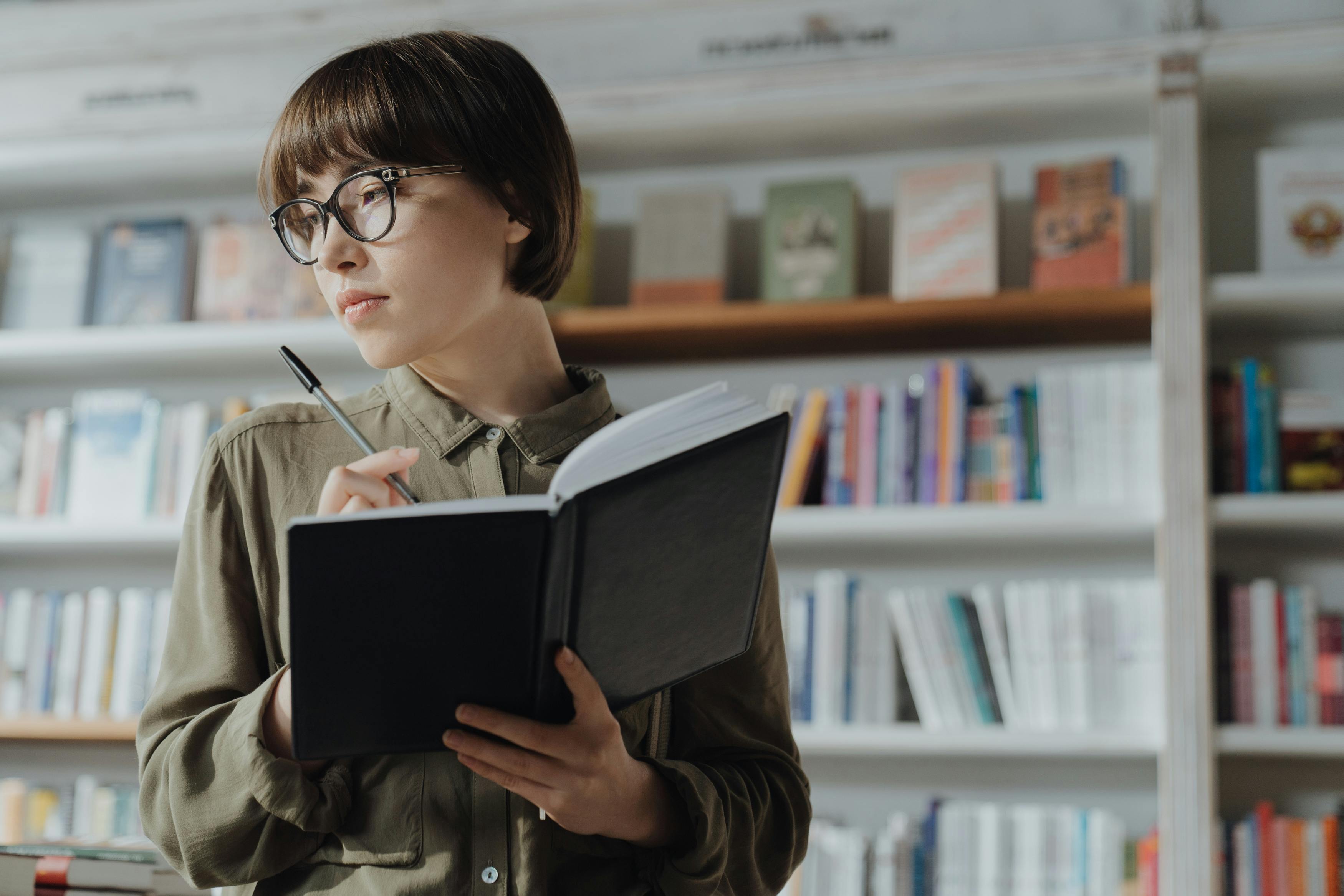 Mujer joven estudiando con un cuaderno sobre pronombres en portugués.