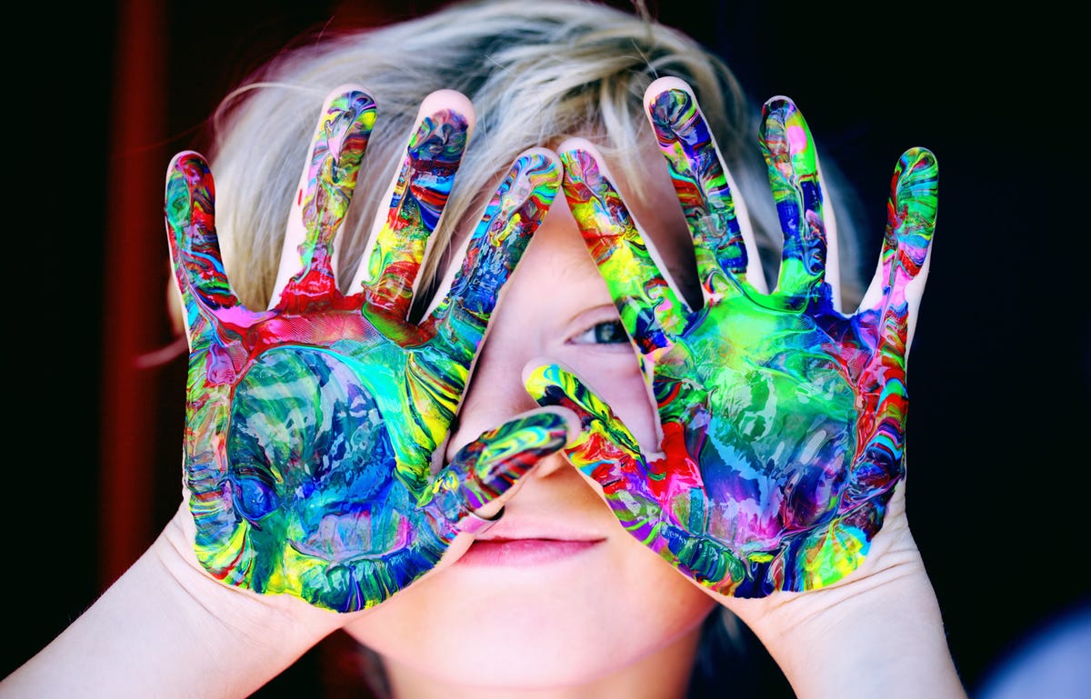 Un niño con las manos pintadas de colores