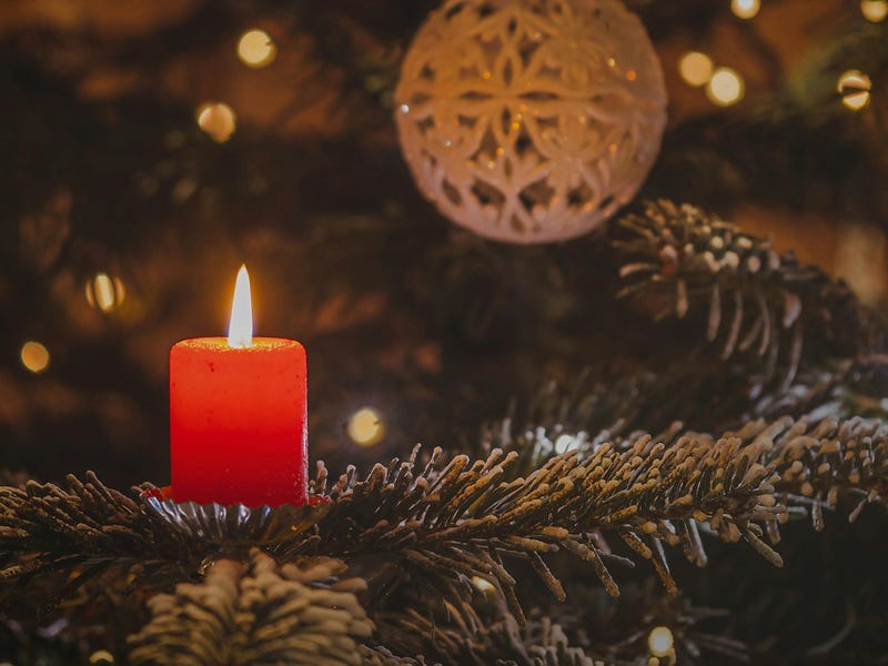 Velita roja y un árbol de Navidad con decoración blanca para la fiesta de Yule.
