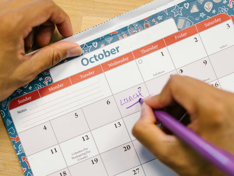 Hombre escribe en su calendario con los días en inglés sus actividades para la semana.