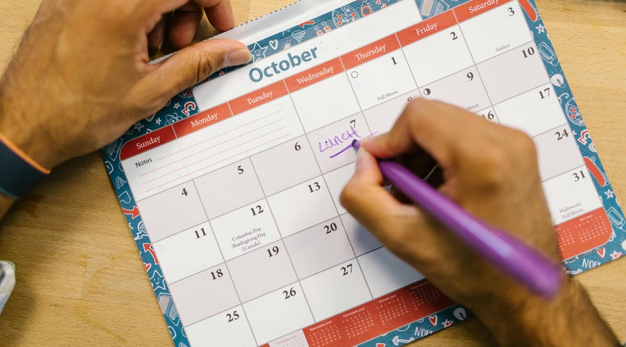 Hombre escribe en su calendario con los días en inglés sus actividades para la semana.