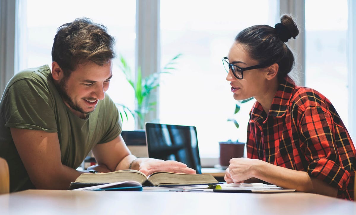 Estudiantes practicando inglés en una clase personalizada de Berlitz con material de estudio