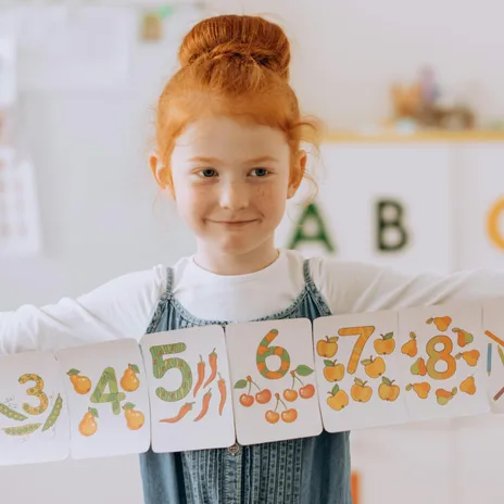 Niña peliroja con cards de los números en inglés para niños.