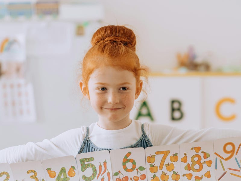 Niña peliroja con cards de los números en inglés para niños.